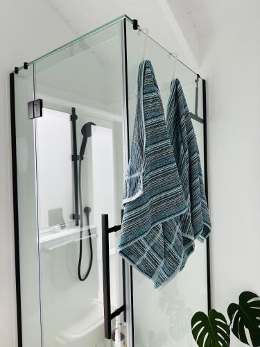 a glass shower stall with a towel hanging from it at Luxury Poolside Studio Near Hobbiton in Matamata
