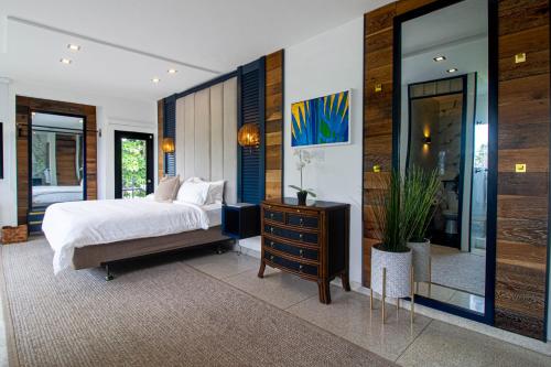 a bedroom with a bed and a dresser and a mirror at Villa Azure Ocean Park's Seaside Luxe Retreat in San Juan