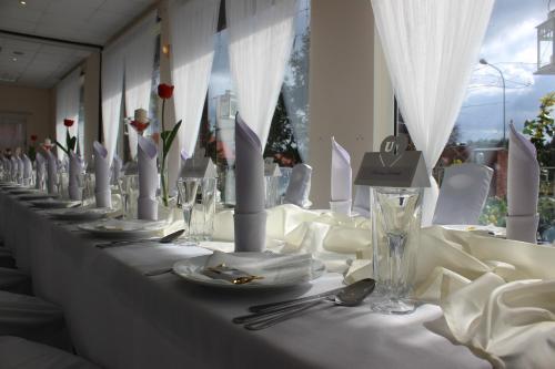 ジェロナ・グラにあるStary Zajazdの白いテーブルクロスと銀器付きの長テーブル