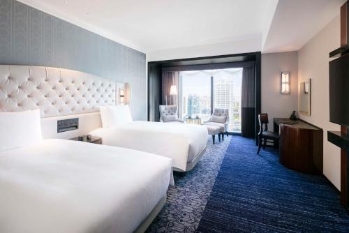横浜市にあるヒルトン横浜のベッド2台とデスクが備わるホテルルームです。