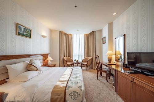 a hotel room with a bed and a flat screen tv at Tan Son Nhat Saigon Hotel in Ho Chi Minh City