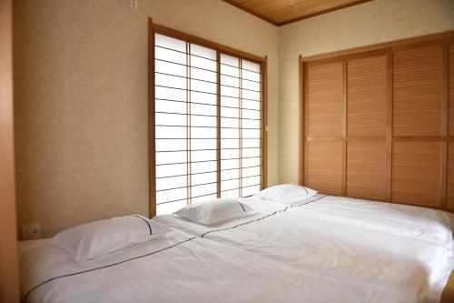 名古屋市にあるPeace & Harmonyの窓付きの客室で、白い大型ベッド1台が備わります。