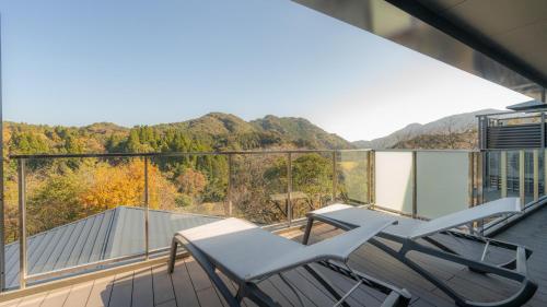 a balcony with two chairs and a view of the mountains at OND HOTEL（オンドホテル） in Takeo