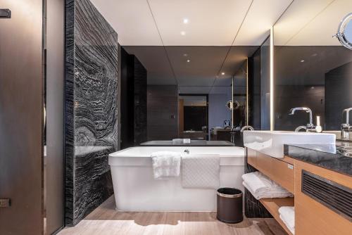 a bathroom with a large tub and a sink at Shenzhen Dameisha Kingkey Palace Hotel in Shenzhen