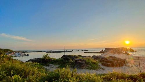 a beach with the sun setting over the water at Group Sea Bed and Breakfast in Xiaoliuqiu