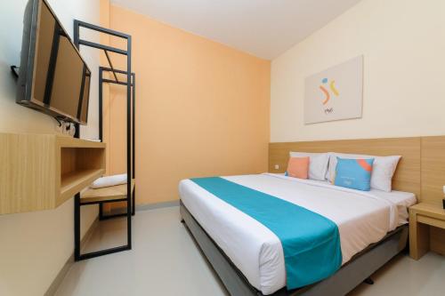 Habitación de hotel con cama y TV en Sans Hotel Cibanteng Dramaga Bogor en Bogor