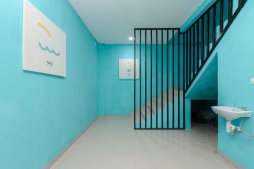 La salle de bains est pourvue de murs bleus, d'un lavabo et d'un escalier. dans l'établissement Sans Hotel Cibanteng Dramaga Bogor, à Bogor