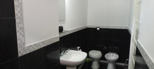 a black and white bathroom with a toilet and a sink at Hostal Adelita in Moisés Ville