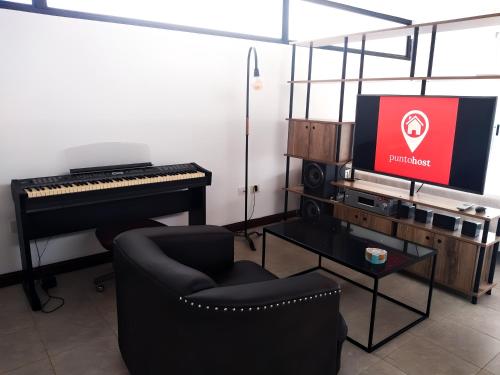 Sala de estar con piano, silla y TV en Hermoso Departamento Unico en La Plata