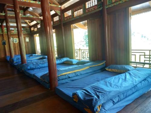 a row of blue beds in a room with windows at Bình Bản Liền Homestay - Vang A Binh in Bắc Hà