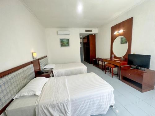 um quarto de hotel com duas camas e uma televisão em Hotel Wisata Indah Sibolga em Sibolga