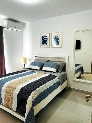 um quarto com uma cama e um espelho grande em Apto 1 Habt Crisfer Punta Cana em Punta Cana