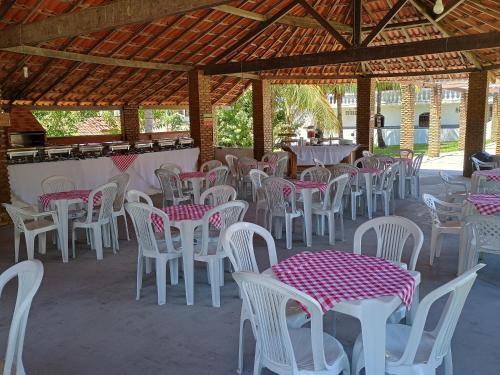 un grupo de mesas y sillas blancas bajo un pabellón en Pousada Villa do Mar, en Itaparica
