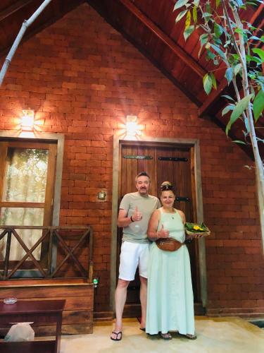 a man and a woman standing in front of a brick building at Jungle Shades villa - Habarana in Habarana