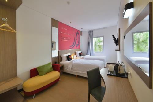 a hotel room with two beds and a chair at Zodiak Sutami by KAGUM Hotels in Bandung