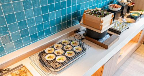 a kitchen counter with cupcakes on a tray and a counter top with at Grids Premium Hotel Kumamoto in Kumamoto