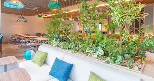 a seating area with plants and tables in a restaurant at Grids Premium Hotel Kumamoto in Kumamoto