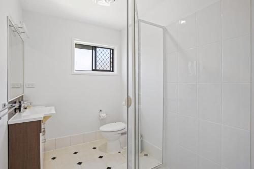 a white bathroom with a shower and a toilet at Windsor Cosy 2-Bedroom Unit in Quiet Neighborhood in Brisbane