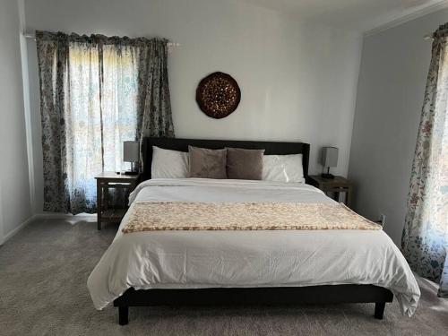 a bedroom with a large bed and two windows at Sovereign Cottage - Farm Land/Hot Tub/Outdoor Area in Fuquay-Varina