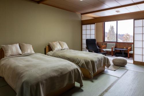 1 dormitorio con 2 camas, silla y ventana en Kogakuro, en Myoko