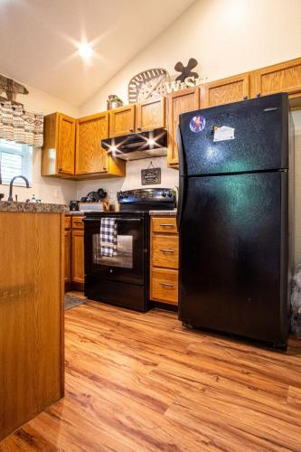 a kitchen with a black refrigerator and wooden cabinets at Cabin C in the Gatlinburg Art & Craft Community in Gatlinburg