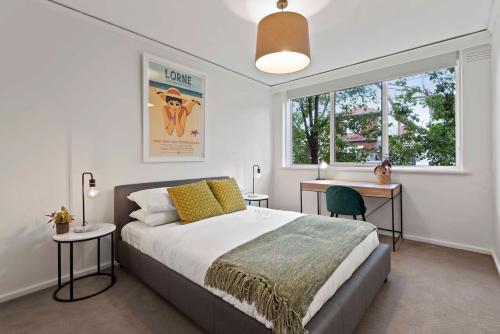 Schlafzimmer mit einem Bett, einem Schreibtisch und einem Fenster in der Unterkunft Urban Retro - Experience Vibrant Courtyard Charm in Melbourne