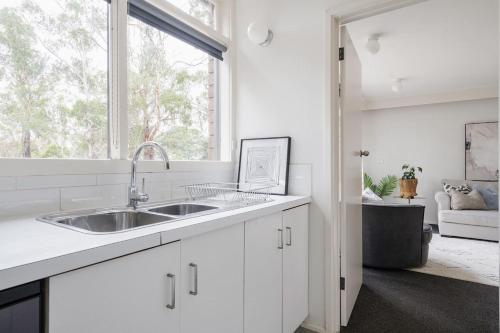 a white kitchen with a sink and a window at Uncover Mount Eliza's Charm from this Local Stay in Mount Eliza