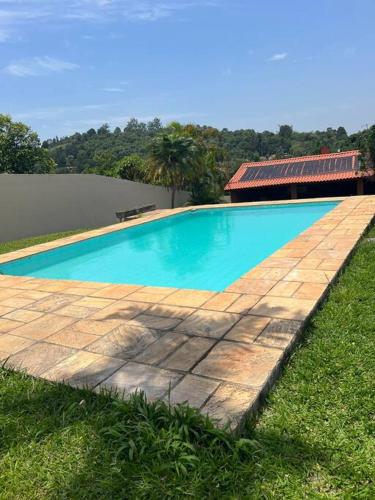a swimming pool with a wooden path in the grass at Linda chácara reformada. in Itu