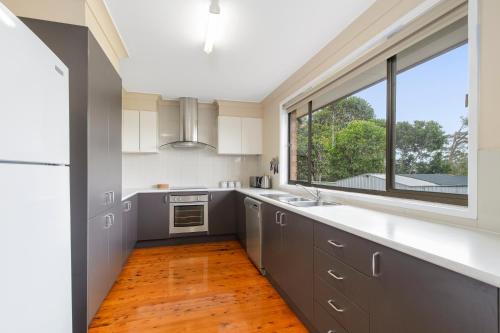 a kitchen with white cabinets and a large window at 19 Pindari Parade Port Macquarie in Port Macquarie