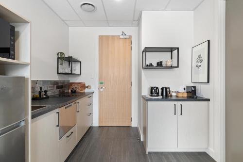 a kitchen with white cabinets and a wooden door at 12th Avenue Suites in Queenstown