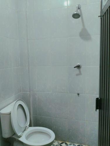 een badkamer met een wit toilet en een douche bij GRHA RAF HOMESTAY in Makale