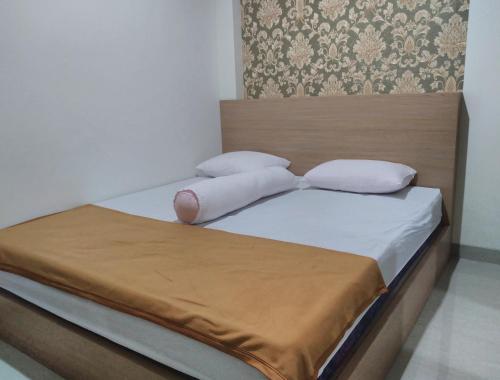 Una cama con sábanas blancas y almohadas. en GRHA RAF HOMESTAY, en Makale