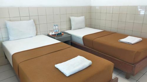 two beds with brown and white sheets in a room at HOTEL ANEKA BARU in Sleman