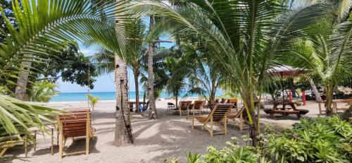 einen Strand mit Stühlen, Tischen und Palmen in der Unterkunft Sulu Sunset Beach Resort in Nauhang