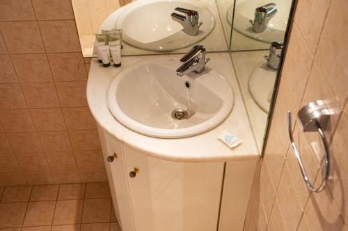 a bathroom with a white sink and a mirror at Sunset Breeze Villa and Apartments in Tourlos