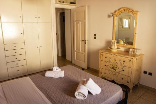 a bedroom with a bed and a dresser and a mirror at Sunset Breeze Villa and Apartments in Tourlos