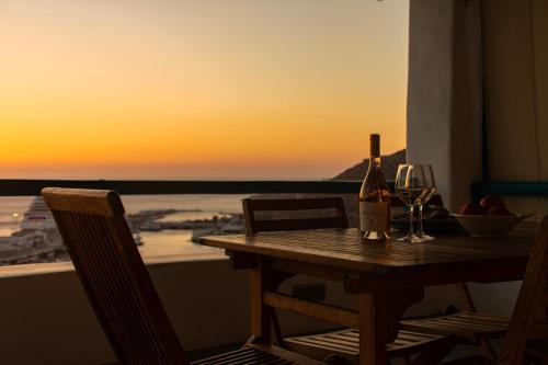 a table with a bottle of wine and two glasses at Sunset Breeze Villa and Apartments in Tourlos