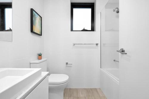 a white bathroom with a toilet and a shower at New Modern 2BR 2baths Apt in Homebush Sleeps 6 in Sydney