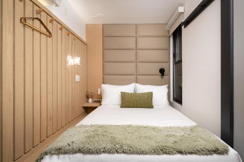 a bedroom with a large white bed with a large headboard at Little Charlie Hotel in New York