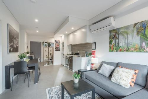 a living room with a couch and a kitchen at King bed Apt Study Homebush Sleeps 3 in Sydney