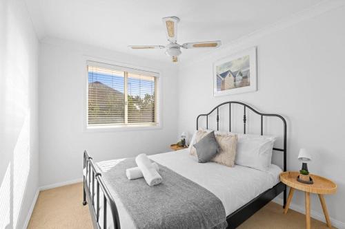 a white bedroom with a bed and a window at 3 Bdrms Duplex in Greystanes in Merrylands