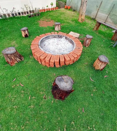 a fire pit in the grass with logs around it at Moonlight Chillers By LexStays in Yedapalli