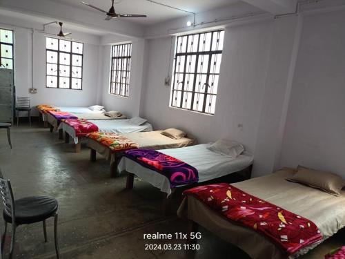 - une rangée de lits dans une chambre avec fenêtres dans l'établissement Muzaffarpur Guest House, à Muzaffarpur