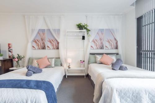 two beds in a room with two windows at 2BR Apt in Hurstville 1Min To Train Station Sleep 8 in Sydney