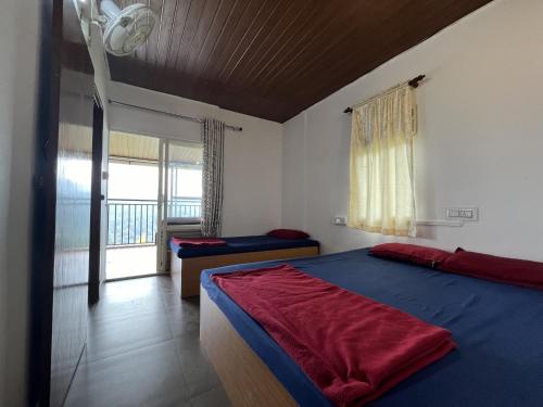 a bedroom with a blue bed and a balcony at Theeram Agro Farm Hill Resort Vagamon in Vagamon