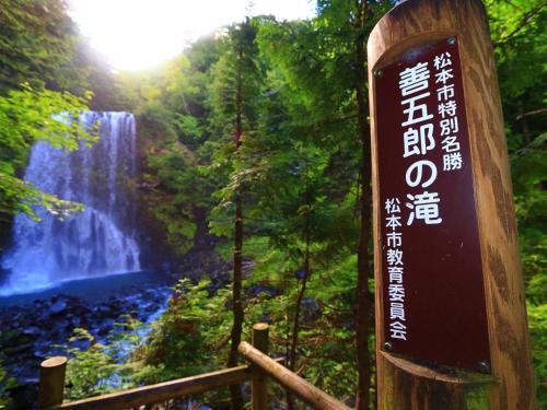 a sign in front of a waterfall in a forest at 雀の宿 やぐら in Matsumoto