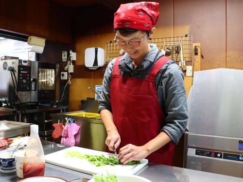 a man in a kitchen preparing food on a cutting board at 雀の宿 やぐら in Matsumoto