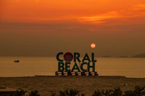 a sign on the beach with the sunset in the background at The Oceanfront Apartment At Cam Ranh in Cam Ranh