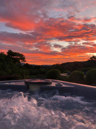 a hot tub with a sunset in the background at Dulguigan Downs Farm House in Condong