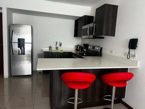 a kitchen with red bar stools and a refrigerator at Comodidad y privacidad en un solo lugar in Heredia